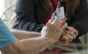 A nurse holding a residents hand