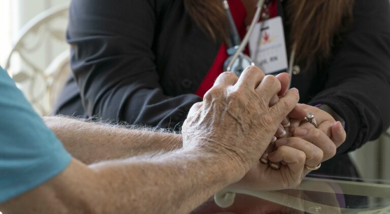 A nurse holding a residents hand