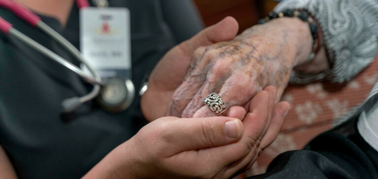 Nursing holding residents hand