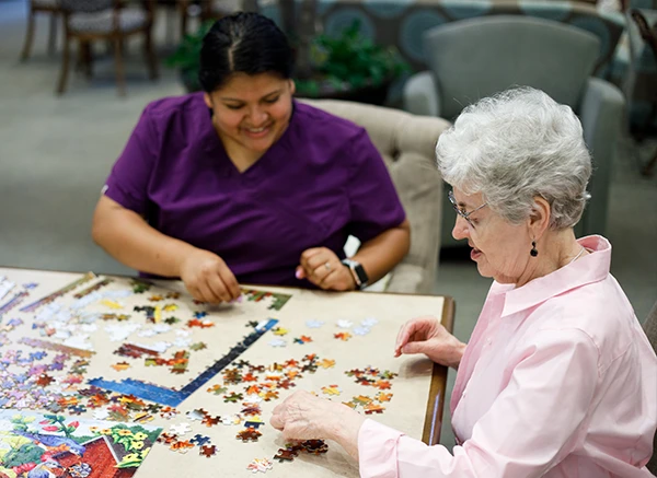 Resident and care giver working on a puzzle
