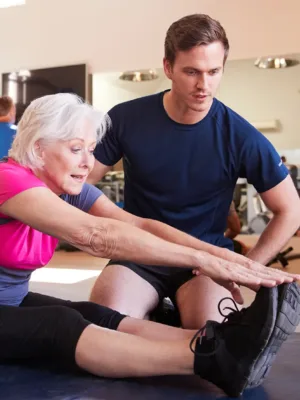 Fitness - woman stretching with trainer